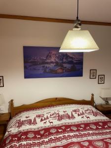 a bedroom with a bed with a painting on the wall at Apartments Casa Metz in Santa Cristina Gherdëina