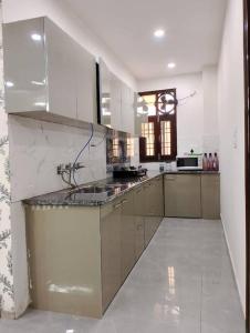 a large kitchen with white walls and stainless steel appliances at Homlee-Vintage Green 2BHK with Terrace & fort View in New Delhi