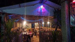 un grupo de personas sentadas en un restaurante por la noche en Nilaveli Beach Rooms, en Nilaveli