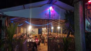 a group of people sitting at a restaurant at night at Nilaveli Beach Rooms in Nilaveli
