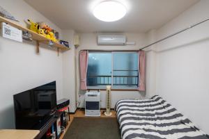 札幌的住宿－Almaz Place #205，一间卧室设有一张床、一台电视和一个窗口。