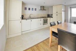 a kitchen with white cabinets and a table and chairs at Host & Stay - Mill in Consett