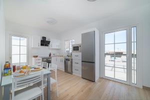 eine Küche mit weißen Geräten und einem Tisch mit Stühlen in der Unterkunft VV Villa Secretos de Yaiza 3 by HH - private pool & BBQ in Yaiza