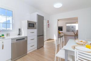 eine Küche mit weißen Geräten und einem Tisch mit Stühlen in der Unterkunft VV Villa Secretos de Yaiza 3 by HH - private pool & BBQ in Yaiza