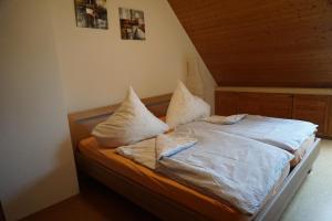 Schlafzimmer mit einem Bett mit weißer Bettwäsche und Kissen in der Unterkunft Ferienwohnung Ampergarten in Grafrath