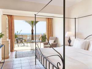 a bedroom with a bed and a view of the ocean at Grecotel Olympia Oasis & Aqua Park in Loutra Killinis