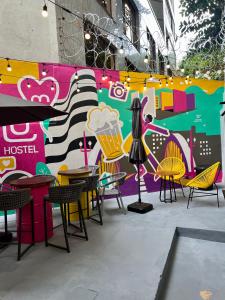 un grupo de mesas y sillas frente a una pared en Belô Hostel, en Belo Horizonte