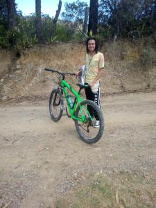 a woman is standing next to a green bike at Estancia Iraka in Ráquira