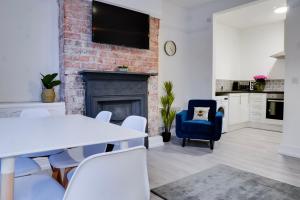 sala de estar con mesa, sillas y chimenea en Stylish 2 bedroom flat - 15 minutes to Liverpool City Centre, en Birkenhead