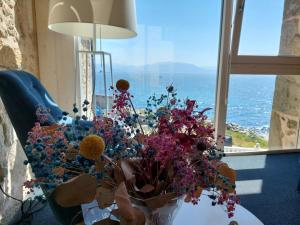 eine Vase mit Blumen auf einem Tisch vor einem Fenster in der Unterkunft Hotel Tematico Do Banco Azul in Kap Finisterre