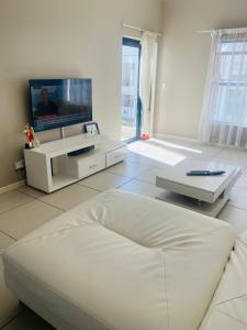 sala de estar blanca con sofá blanco y TV en Greenstone Ridge en Lombardy East