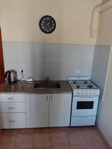 a kitchen with a stove and a clock on the wall at Departamentos Haiti in Bahía Blanca