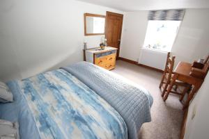 a bedroom with a bed and a desk and a window at Zen Cottage Seatown Cullen in Cullen