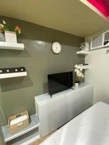 a living room with a tv and a clock on a wall at NA Suites at Pine Suites Tagaytay in Tagaytay