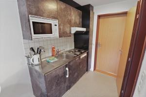 eine kleine Küche mit einer Spüle und einer Mikrowelle in der Unterkunft Studio charmant avec vue imprenable in Saas-Fee