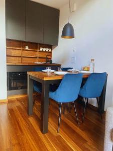 una cucina con tavolo in legno e sedie blu di Olimian Retreat Rosa 421 a Podcetrtek