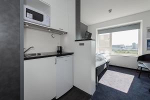 a room with a kitchen and a bed with a window at Cabinn Apartments in Copenhagen