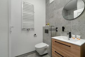 uma casa de banho com um WC, um lavatório e um espelho. em Apartment Szamarzewskiego with Balcony Poznań by Renters em Poznań