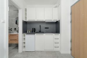 uma cozinha branca com armários brancos e um lavatório em Apartment Szamarzewskiego with Balcony Poznań by Renters em Poznań