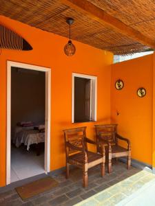 een kamer met 2 stoelen en een oranje muur bij Pousada da Barra in Barra Grande