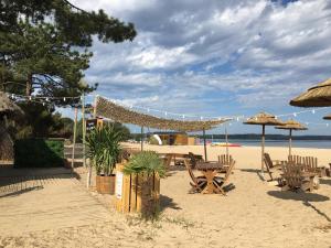 een strand met een tafel, stoelen en parasols bij Détente-famille-lac in Biscarrosse