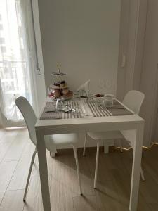 une table à manger blanche avec des chaises blanches et une table dans l'établissement My Petite Maison Milan, à Milan