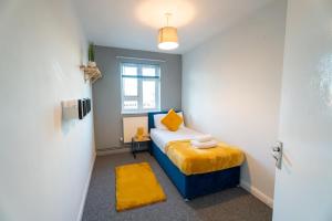 a small bedroom with a bed with a yellow blanket at Cosy Flat 10 mins to Central London sleeps 5 in London