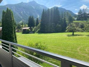 a balcony with a view of a green field and mountains at Natura Aparts in Stanzach