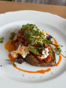 a white plate with a piece of bread with vegetables on it at Dotcampus Roma City Center in Rome