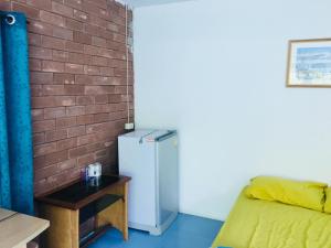Zimmer mit einem Kühlschrank neben einer Ziegelwand in der Unterkunft ลุงยอด เกสต์เฮ้าส์ in Ban Tha Ling Lom