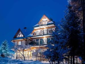 a large house in the snow at night at Studio Apartment with Mountain View in Zakopane