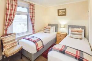 a bedroom with two beds and a window and a chair at Host & Stay - Jackson Cottage in Thirsk