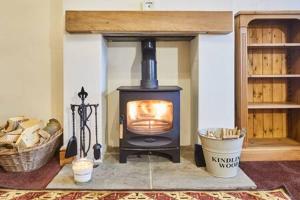 a wood stove in a living room with a basket at Host & Stay - Jackson Cottage in Thirsk