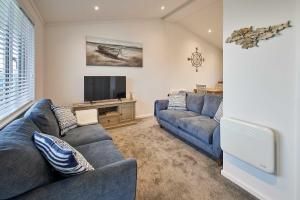 a living room with two blue couches and a tv at Host & Stay - Sea View Road in Bessingby
