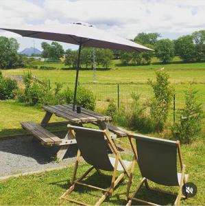 a picnic table and two chairs with an umbrella at Logement insolite au cœur de l'Auvergne in Rochefort-Montagne