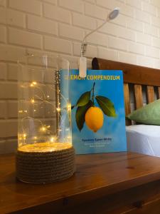 a glass jar with an orange on a table next to a book at Best Kept Secret by the Sea in Famagusta