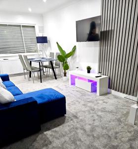 a living room with a blue couch and a table at Cosy 3 bedroom Near Heathrow - 6 beds, sleeps 7, FREE PARKING in Staines upon Thames
