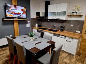 a kitchen with a table with chairs and a tv on the wall at Cherry House in Čatež ob Savi