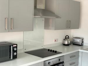 uma cozinha com armários brancos e um micro-ondas em Platform Church View Apartment Hull em Hedon