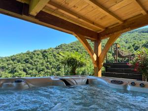 a large hot tub under a wooden roof with a slide at d'une Source in Asperjoc
