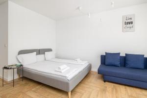 1 cama y 1 sofá azul en una habitación en Chmielewskiego Lovely Studio, en Szczecin