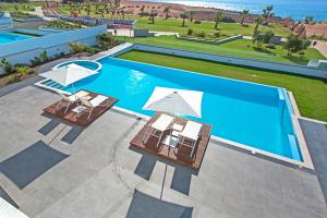 two chairs and umbrellas next to a swimming pool at Vivo Mare Beachfront-Seaview Villas in Ayia Napa