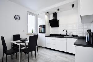 een keuken met witte kasten en een tafel en stoelen bij RentPlanet - Apartament Biały Dom in Kołobrzeg