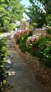 a garden with flowers and a stone wall at Apartments Mara in Mali Lo&scaron;inj