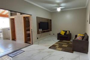 a living room with two chairs and a flat screen tv at Área de Lazer Macaúba Sabiá in Ribeirão Preto