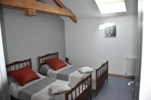 two beds in a room with white walls and red pillows at Le Cintrium in Viala-du-Tarn