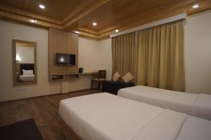 a hotel room with two beds and a television at Kunden Village Resort in Gangtok