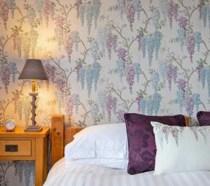 um quarto com uma cama com papel de parede floral em Sheriff Lodge em Matlock