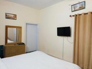 イスラマバードにあるLuxury Moon Guest Houseのベッドルーム(ベッド1台、ドレッサー、テレビ付)