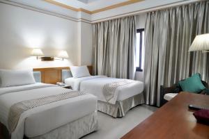 een hotelkamer met twee bedden en een bureau bij Kosa Hotel & Wellness Center in Khon Kaen +51 foto's